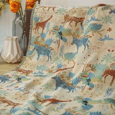 a blanket with animals on it next to vases and flowers