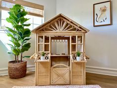 a doll house made out of wicker with a potted plant next to it