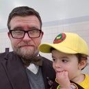 a man standing next to a little boy wearing a yellow hat and glasses on his head