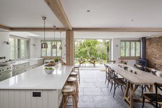 an open kitchen and dining area with brick walls, white counter tops and wooden chairs