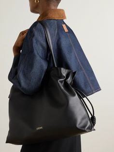 Though this tote is a relatively recent addition to Loewe's 'Flamenco' line, the style is nothing short of iconic. Introduced in the '70s, it's defined by the drawstring closure that creates supple folds in the leather, almost as if it were silk. This 'XL' version has been made in Spain, stamped with the house's 'Anagram' and lined in herringbone fabric. Loewe Flamenco Bag Outfit, Loewe Tote Bag, Loewe Cushion Tote, Loewe Summer Bag, Loewe Flamenco Black, Black Loewe Puzzle Bag, Herringbone Fabric, Loewe Bag, Sports Trousers