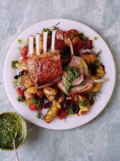 a white plate topped with meat and veggies next to a bowl of pesto