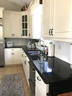 a kitchen with white cabinets and black counter tops is seen in this image from the front view