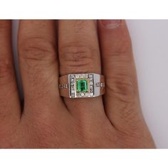 Natural 0.77 Carat Emerald and 1.01 Carat Diamond 18K Gold Mens Ring  Mens Ring boasting an emerald-cut, vivid green emerald center stone. The emerald weighs 0.77 carats and is secured in a prong setting. The center stone is paired with an additional total of 28 diamond stones. 6 of the diamonds are round-cut, weighing 0.15 carats total. These diamonds are placed above and below the emerald. The other 22 diamonds are princess-cut, weighing 0.86 carats total. These diamonds are placed on either side of the emerald and along the shank of the ring. All diamonds are secured in a channel setting. The ring is crafted from 18k white gold and sized at a USA 9.5. An alluring piece exemplifying masculine charm and elegance.   Item Details: - Type: Men's Ring   - Metal: 18K White Gold  - Weight: 8.88 Green Diamond Signet Ring For Anniversary, Anniversary Green Diamond Signet Ring, Formal Green Emerald Signet Ring, Green Diamond Signet Ring In Fine Jewelry Style, Green Prong Set Signet Ring For Formal Occasions, Fine Jewelry Green Signet Ring With Center Stone, Green Signet Ring With Center Stone For Anniversary, Anniversary Green Signet Ring With Center Stone, Green Emerald Signet Ring With Prong Setting