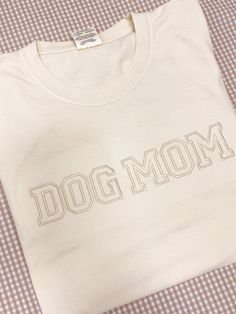 Details A simple and trendy tee for the ultimate dog mom fashionista. This design features a Comfort Colors t-shirt with dog mom embroidered in a varsity font across the front. Choose between Seafoam and Cream. Due to lighting and differences in monitors, actual colors may vary slightly from what appears online Materials 100% Cotton Shipping Each Custom Embroidered Crew Neck is handmade to order & may have a processing time of up to 14 business days. If this sweatshirt is ordered with other item Dog Mom T Shirt, Dog Mom Embroidery, Cotton T-shirt With Letter Embroidery For College, Varsity Cotton T-shirt With Embroidered Graphics, White Varsity T-shirt With Letter Embroidery, Cotton Varsity Top With Embroidered Text, Sporty Cotton T-shirt With Embroidered Text, White Varsity T-shirt With Embroidered Graphics, Varsity Cotton T-shirt With Letter Embroidery