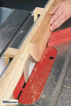 a person using a circular saw to cut wood with a red piece of material in front of them