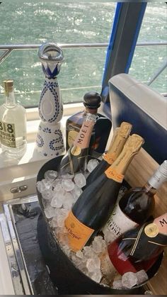 an ice bucket filled with bottles of wine on top of a table next to the ocean