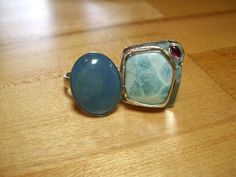 "The stone is a soft and lovely blue. I put it next to a Larimar so you can tell the color if it is different on your screen. ( This listing is for the Kyanite ring only. The Larimar is listed separately.) I have 5 of these stones and every one is quite different. This is the one that you will buy here though. (Then, I will need another picture. Drat!) I have set it in a plain wall bezel on a wide domed floral band that has flowers and icanthus leaves. The band is 4mm wide and you may need a lar One Of A Kind Blue Ring Jewelry, One Of A Kind Blue Ring, One-of-a-kind Blue Ring, Unique Blue Gemstones For Anniversary, Unique Blue Gemstones In Sterling Silver, One Of A Kind Blue Sterling Silver Rings, Plain Wall, Kyanite Ring, Studio Cards