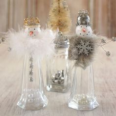 two snowmen are sitting next to each other in small glass vases on a table