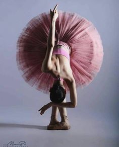 a woman in a pink tutu is doing a handstand on her head