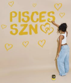 a woman standing in front of a wall with the words pisces szn painted on it