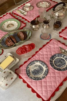 a table topped with plates and bowls filled with food on top of a white table cloth