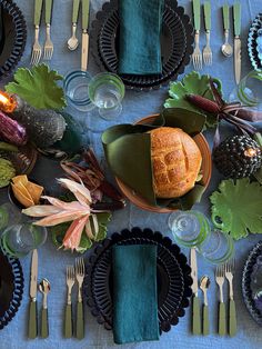 a table set with plates, silverware and green napkins for an autumn dinner