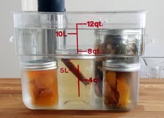 three jars filled with liquid sitting on top of a wooden table