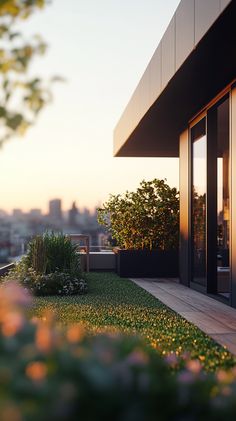 a balcony with grass and flowers in the foreground, overlooking a cityscape