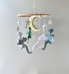 a mobile with stars, moon and dragon hanging from it's sides on a white wall