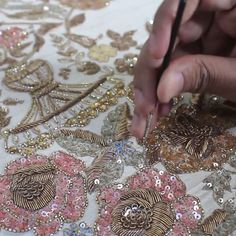 a person is working on an embroidered material with scissors and thread, surrounded by sequins