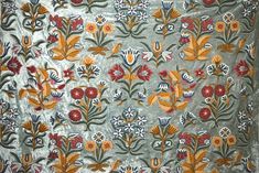 an embroidered cloth with flowers and leaves on it, in grey color is the center piece of this fabric