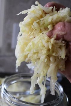 a person is holding up some food in a glass bowl on the stove top, with another hand reaching for it