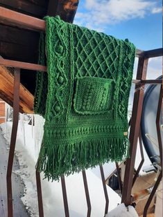 a green scarf hanging on the side of a fence