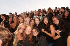 a group of young women standing next to each other in front of a large crowd