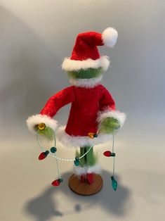 a santa clause doll is posed on a small wooden stand with christmas lights attached to it