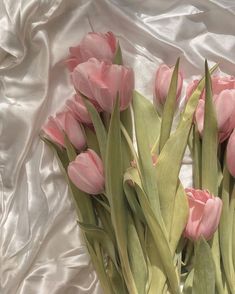 some pink tulips are in a vase on a white cloth