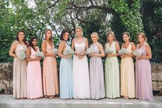 a group of women standing next to each other in long dresses and holding bouquets