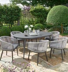 an outdoor table and chairs in the middle of a garden