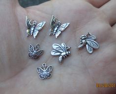 small silver butterfly charms on a person's palm, set in various shapes and sizes