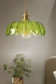 a green lamp hanging over a table next to a potted plant