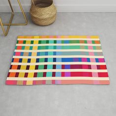 a multicolored area rug on the floor next to a basket and planter