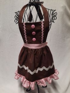 a brown and pink apron with buttons on the front is attached to a metal rack