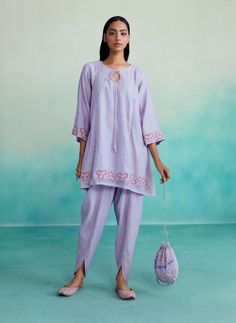 Introducing our ethereal lavender kurta set - a captivating two-piece ensemble crafted in fine chanderi fabric. The kurta features intricate hand embroidery, delicate mirror work, and elegant hangings for added grace. Paired with ankle-length tulip pants, this set exudes charm and style. Complete your enchanting look with matching juttis and elevate your wardrobe with this ethereal masterpiece today! Spring Cotton Silk Sets With Mirror Work, Chanderi Pant Set With Chikankari Embroidery And Straight Kurta, Chikankari Chanderi Pant Set For Navratri, Spring Cotton Palazzo Set With Mirror Work, Navratri Chikankari Chanderi Pant Set, Designer Purple Cotton Kurta, Festive Cotton Pant Set With Mirror Work, Purple Chanderi Kurta With Floral Embroidery, Lavender Floral Embroidery Sets For Eid