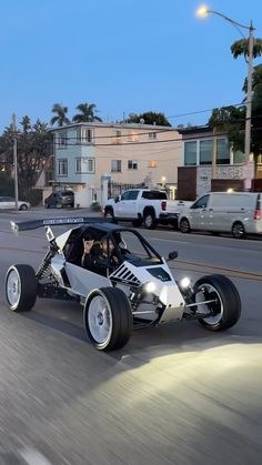 two people riding in an electric vehicle on the street at night with other cars behind them