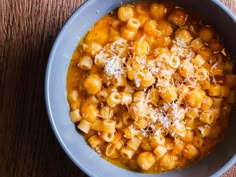 a blue bowl filled with macaroni and cheese on top of a wooden table