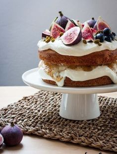 a cake sitting on top of a white plate covered in frosting and figs