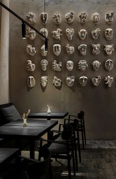 a wall with many masks on it and some chairs in front of the table top