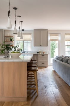 a kitchen and living room are shown in this modern style home with wood flooring