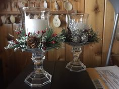 two glass vases with christmas decorations sit on a table