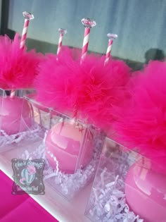 pink candles are sitting in clear vases filled with tissue pom - poms