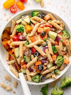 a white bowl filled with pasta salad next to broccoli