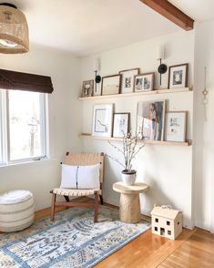 a living room filled with furniture and framed pictures on the wall behind a chair in front of a window