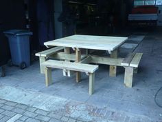 a wooden picnic table and benches in front of a garage