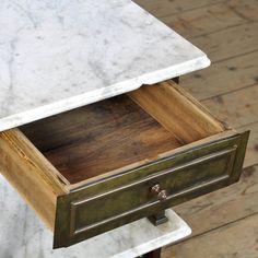 a marble topped end table with drawers on it's sides and one drawer open