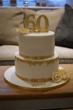 a white and gold wedding cake with the number 60 on top