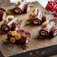 several pieces of chocolate on a cutting board with orange slices and rosemary sprigs