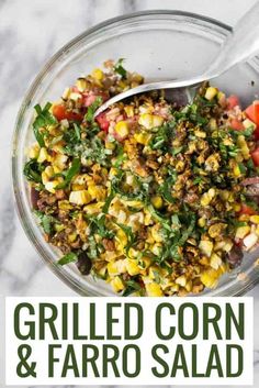 grilled corn and faro salad in a glass bowl with a spoon on the side