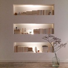 a vase with a flower in it sitting next to some bookshelves on the wall