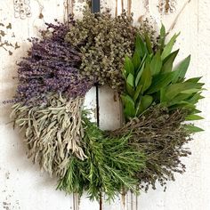 a wreath made out of dried herbs and greenery hangs on a white painted door